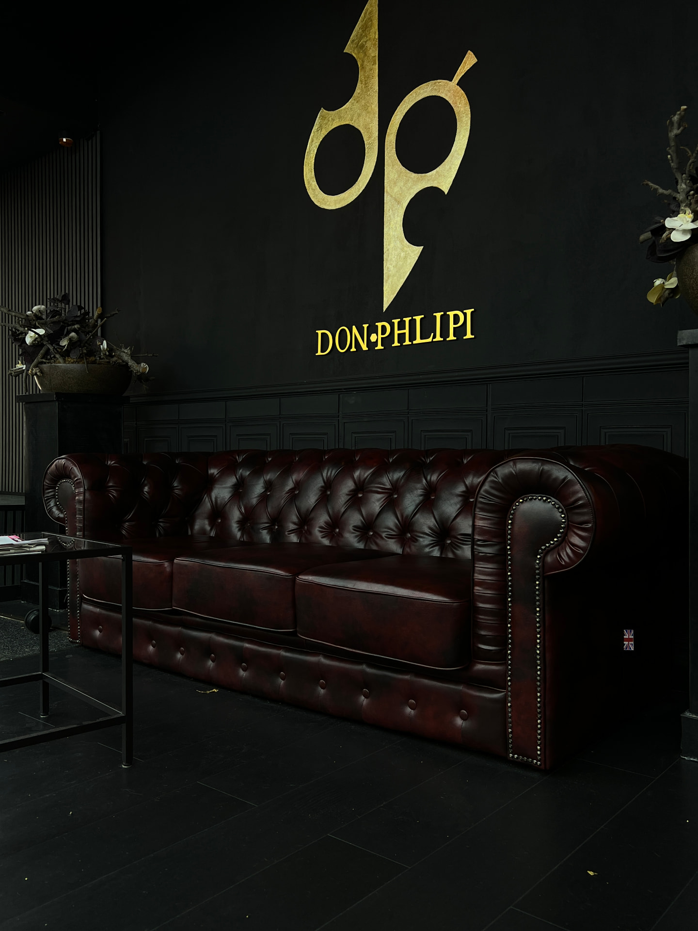 Don Phlipi waiting area with red leather sofa and gold logo